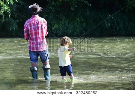 Father And Son Fishing. Fly Fishing For Trout. Happy Man Family Concept - Fishing And Have Fun Toget