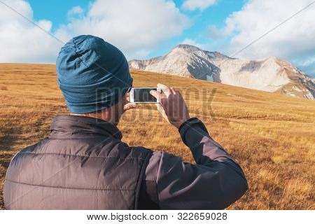 Tourist Traveler Photographs Mountains Covered With Clouds On A Smartphone. A Traveler Takes Photos 