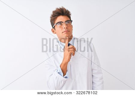 Young handsome sciencist man wearing glasses and coat over isolated white background Thinking concentrated about doubt with finger on chin and looking up wondering