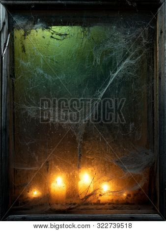 Halloween background with creepy old spider web in a scary dark window