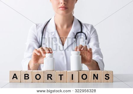 Cropped View Of Doctor Touching Bottles On Cubes With Abortion Letters