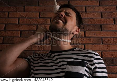 Depressed Man With Rope Noose On Neck Near Brick Wall, Low Angle View