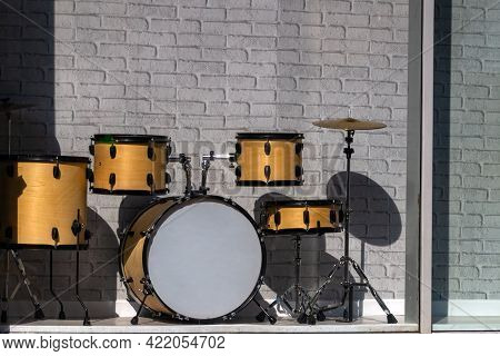 Wood Drum Set Behind Glass On Display Against A Gray Brick Wall
