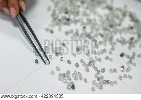 Manual Sorting Of Diamonds. A Hand With Tweezers Transfers Diamonds From One Pile To Another. Discar