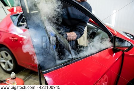 Car Service Worker Cleans Interiror With Steam Cleaner