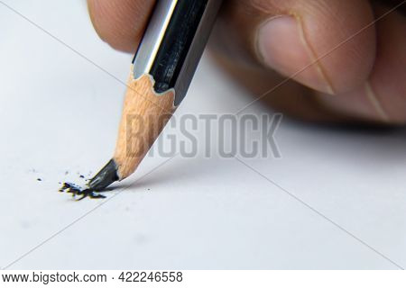 Fingers Holding A Pencil And Nib Broken While Writing On White Paper