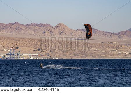 Eilat, Israel - May 24th, 2021: A Man Kite Surfing Off The Shore Of Eilat, Israel, With The Jordania