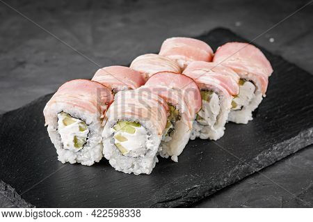 Appetizing Sushi Roll With Philadelphia Cheese Cucumber And Bacon On A Black Stone Plate