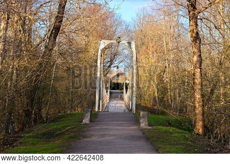 Old Hanging Footbridge Across A Small River In Estonia At Spring