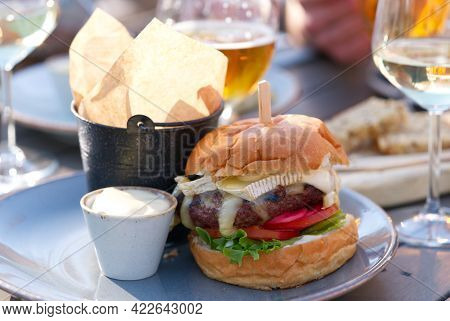 People Sit In The Bar And Eat Juicy Burgers With Wine And Beer