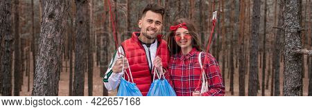Happy Couple With Trash Bags Holding Pick Up Tools In Forest, Banner.