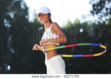 woman rotates hula hoop on nature background