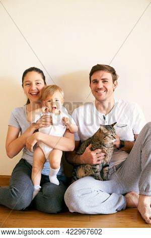 Mom Keeps A Little Girl On Her Lap, And Dad Keeps A Tabby Cat On His Lap