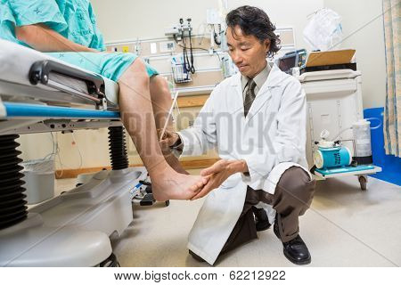 Full length of neurologist examining patient's tendon