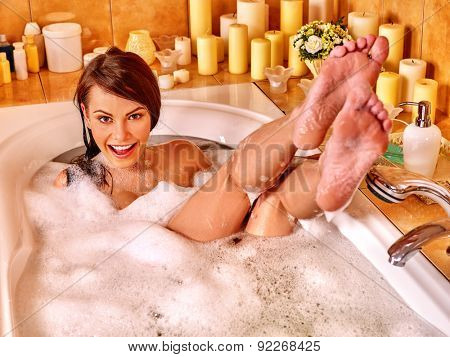 Woman relaxing at water in bubble bath. Visible bare feet.