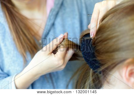 Professional female hairdresser making hairstyle to young woman with long hair. Babette hairstyle . Fashion concept