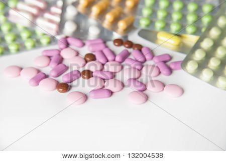 View on scattered pills and tablets in packeges on white background.From above