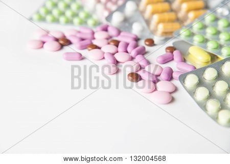 View on scattered pills and tablets in packeges on white background.From above