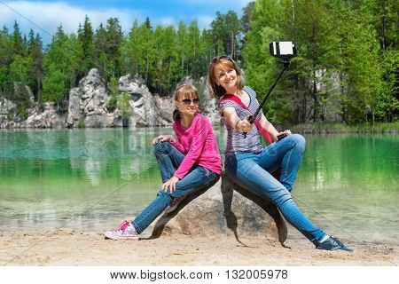Mother and daughter are doing Selfe on the shore of Piskovna lake. National Park of Adrspach-Teplice rocks. Rock Town. Czech Republic.