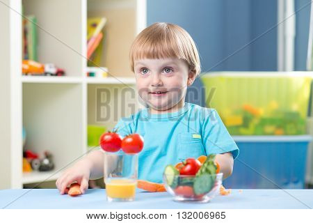 Cutechild boy eats carrot and other vegetables in room