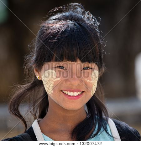 MANDALAY MYANMAR - JANUARY 16 2016: Unidentified young Myanmar girl with thanaka on her smile face is happiness. Thanaka is a yellowish-white cosmetic paste made from ground bark.