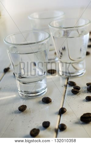 Sambuca in shot glasses and coffee beans on white background