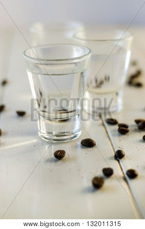 Sambuca in shot glasses and coffee beans on white background