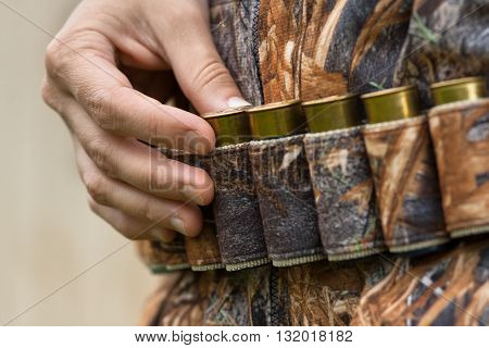 hand of hunter pulling cartridge from the bandoleer closeup