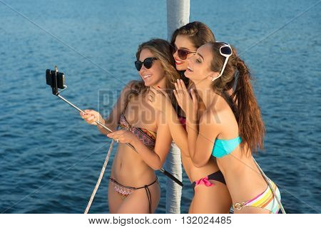 Smiling girls take a selfie. Ladies taking selfies on yacht. We're having so much fun. Vacation time spent at sea.