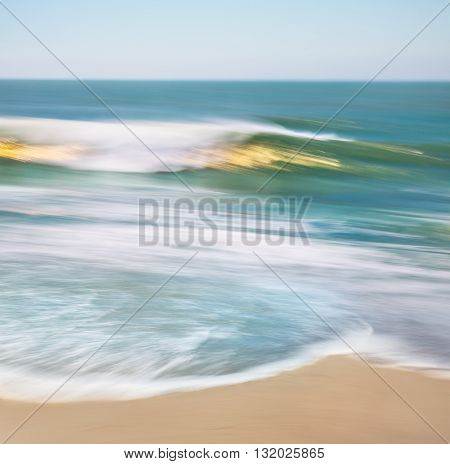 An ocean wave with blurred panning motion and golden sun reflections.
