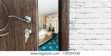 Half opened door to a bedroom. Door handle, door lock. Lounge door half open. Opening door. Welcome, privacy concept. Entrance to the room. Door at white brick wall, modern interior design.