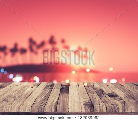 3D render of a wooden deck looking out to a defocussed palm tree island at sunset