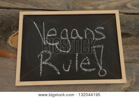 Vegans rule written in chalk on a chalkboard on a rustic background