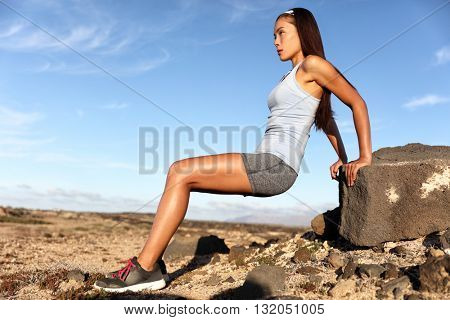 Strength training fitness woman working out arms muscles doing triceps dips. Asian athlete exercising with bodyweight exercises for toned body. Sun suntan skincare in summer desert landscape.