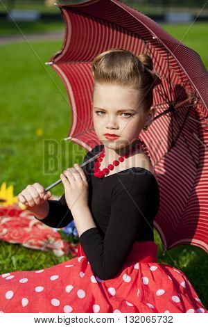 Pin-Up. Lovely little girl in the retro red dress in summer park