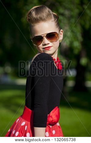 Pin-Up. Lovely little girl in the retro red dress in summer park