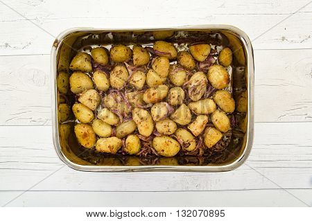 Mustard-crusted new potatoes with shallots in a dish on a rustic wooden table