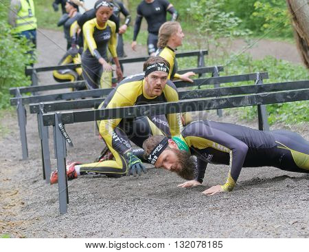 STOCKHOLM SWEDEN - MAY 14 2016: Group of struggling people crawling under bars in the obstacle race Tough Viking Event in Sweden April 14 2016