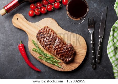 Grilled striploin steak and red wine over stone table. Top view