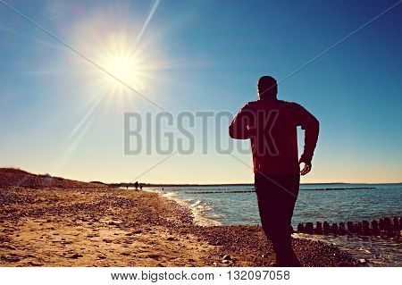 Tall Man In Dark Sportswer Running And Exercising On Stony Beach At Breakwater.