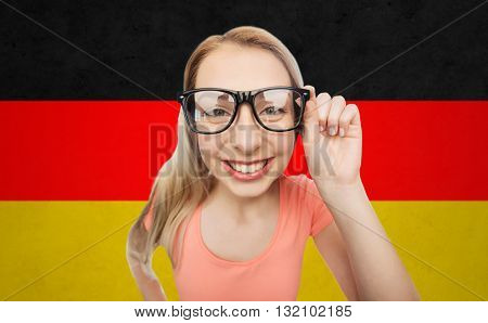 vision, education, national and people concept - happy smiling young woman or teenage girl eyeglasses over german flag background