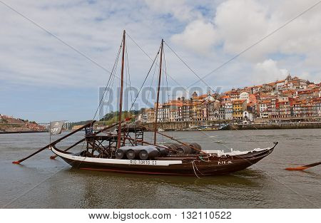 PORTO PORTUGAL - MAY 25 2016: Traditional Rabelo boats (used for port wine transportation) on Douro River in Porto Portugal. Historical part of Porto city (UNESCO site) at the background