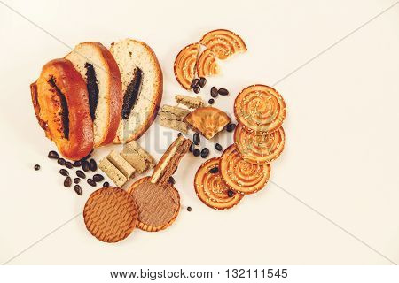 There are Pieces of  Roll with poppyseed,Cookies,Halavah,Chocolate Peas,Tasty Sweet Food on the White Background,Top View,Toned