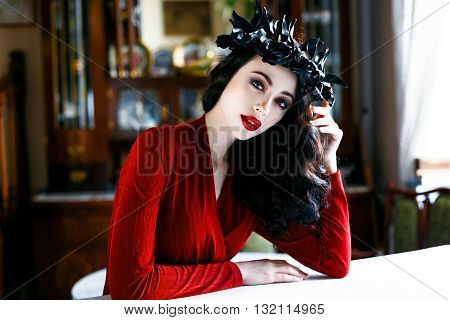 Beautiful model with a rad and black wreath of flowers on her head