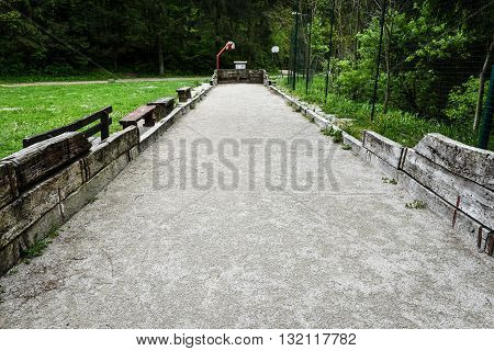 Old field for a game of Petanque or bowling with forest in the background.