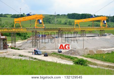 Ovciarsko, Slovakia - May 27, 2016: Yellow bridge crane on construction site of slovak D1 highway. Except for the crane there are some workers and cars.