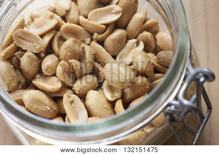 Open canning jar with fried salty peanuts. Selective focus. High angle view