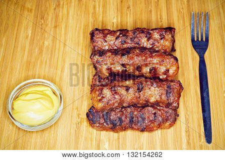 Traditional food Meat Balls "mici" on a rustic wooden table with mustard