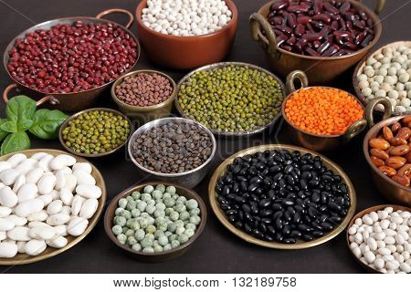 Beans peas and lentils in metal bowls.