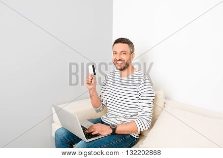 Cheerful Man Doing Internet Shopping With Bank Card And Laptop